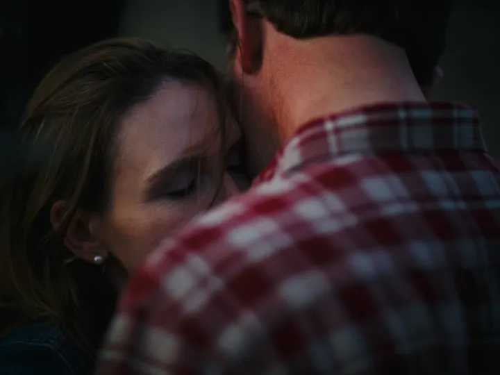 Close engagement portrait of a woman leaning into a man in a plaid shirt