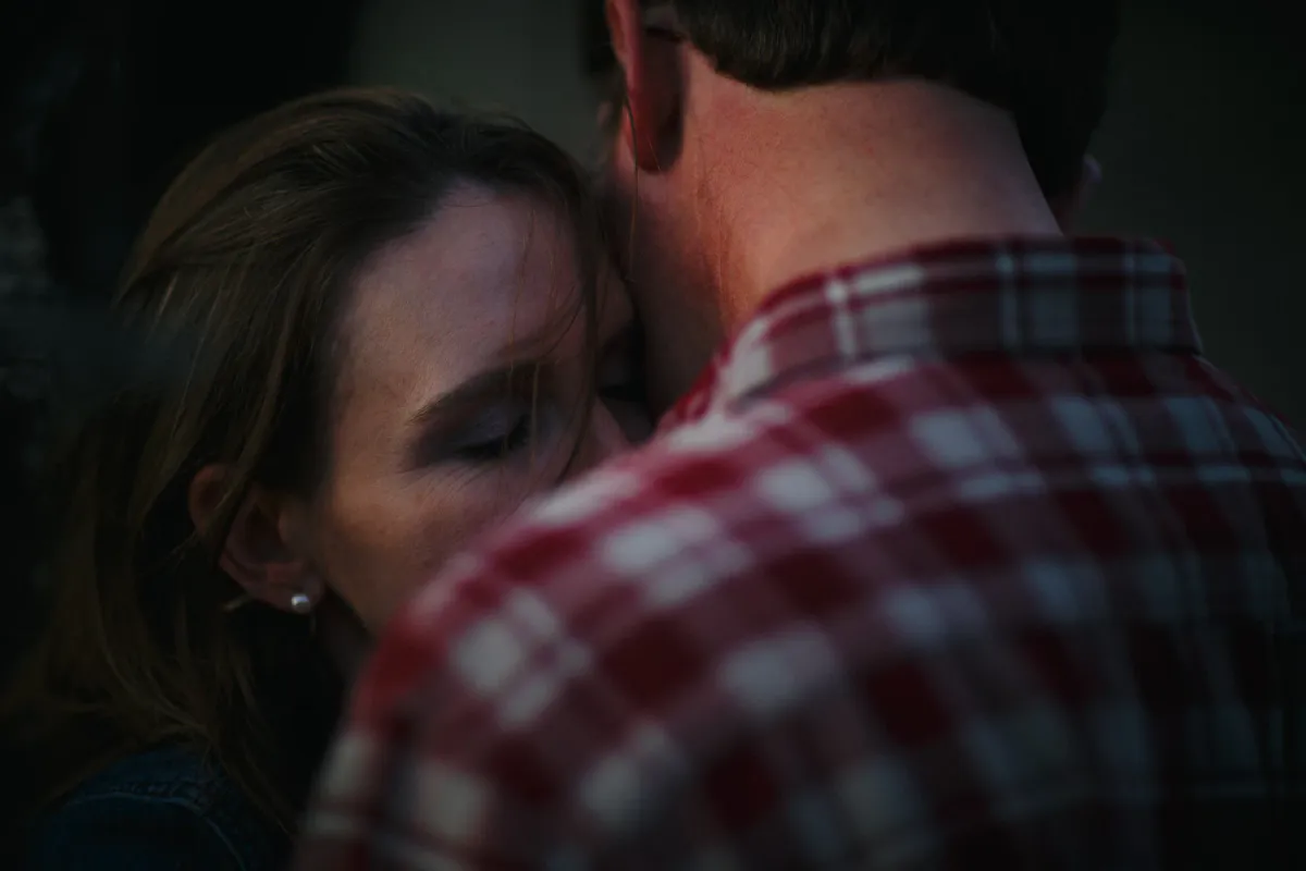 Close engagement portrait of a woman leaning into a man in a plaid shirt