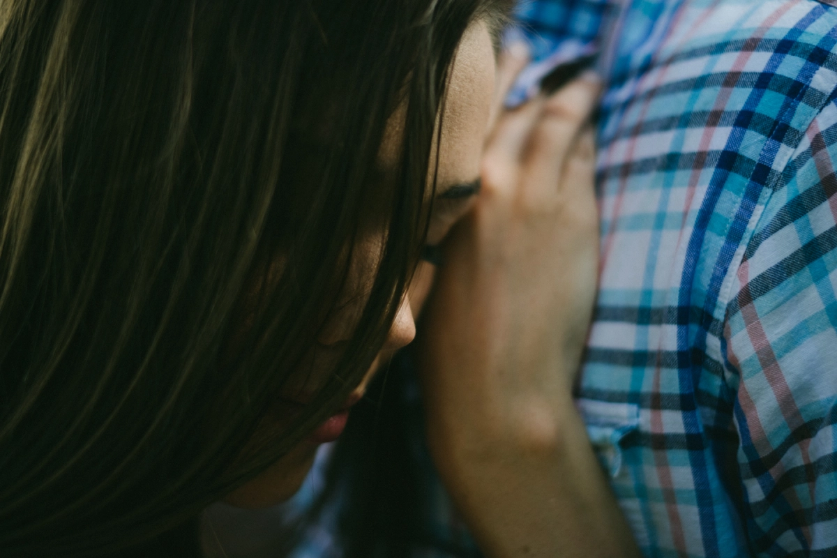 Close engagement portrait of a woman leaning into a plaid shirt