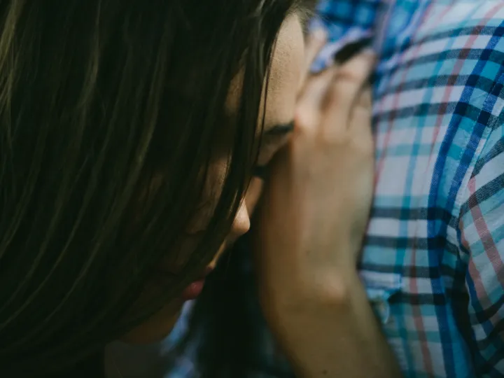 Close engagement portrait of a woman leaning into a plaid shirt