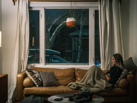 Person reading on a couch beside a winter window while travelling