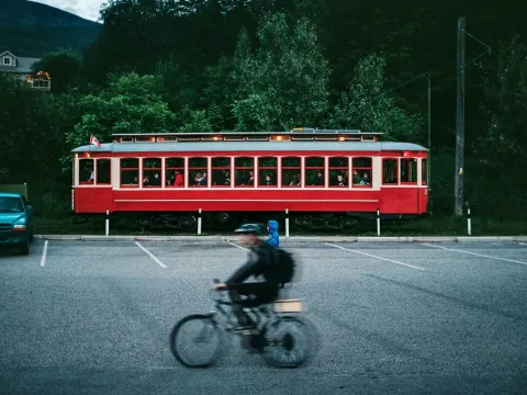 Red streetcar passing as a cyclist moves through the foreground