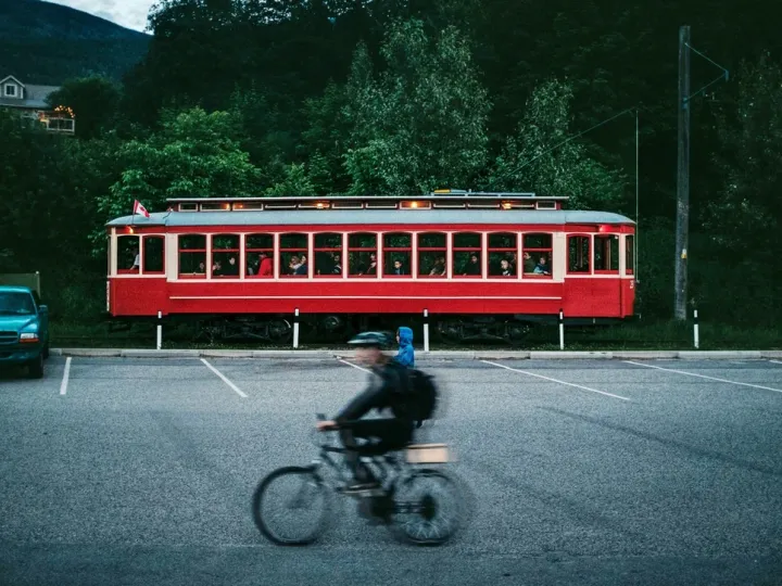 Red streetcar passing as a cyclist moves through the foreground