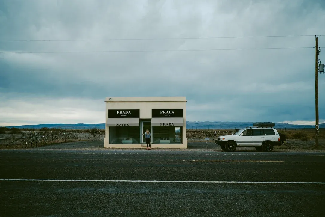 Small roadside building under a heavy sky with a vehicle parked beside it