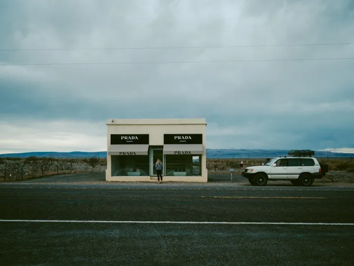 Small roadside building under a heavy sky with a vehicle parked beside it