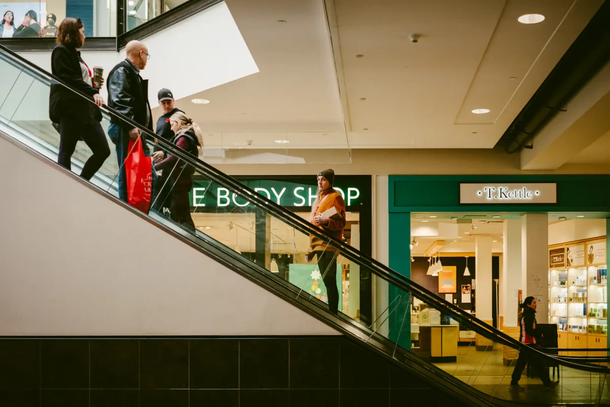 Shoppers riding an escalator inside an Edmonton mall near local retail shops