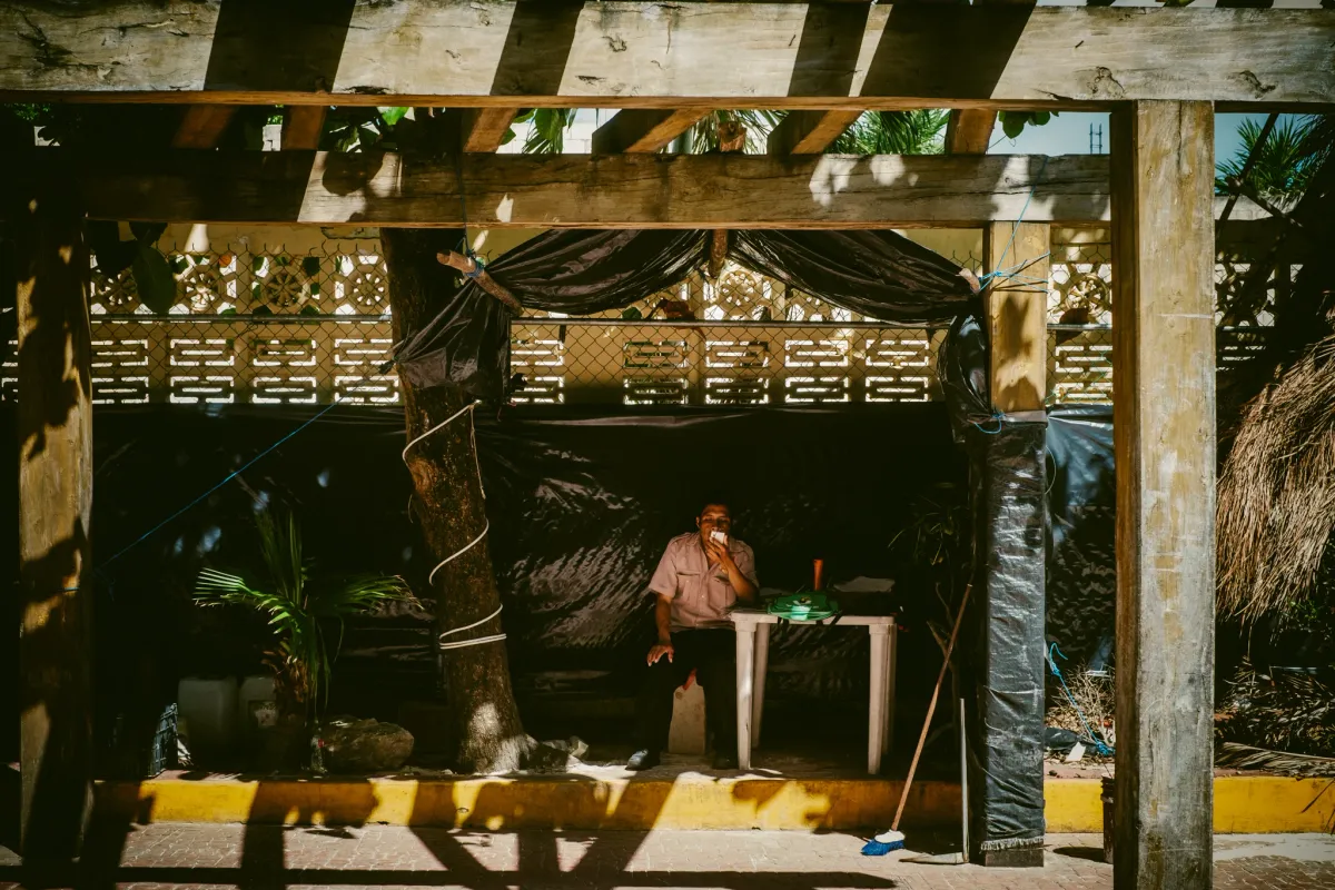 People seated under a rustic shaded lunch hut with bright patterned light