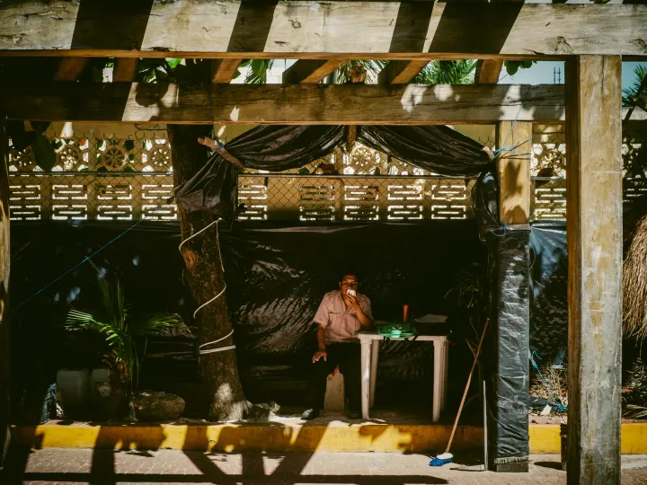 People seated under a rustic shaded lunch hut with bright patterned light
