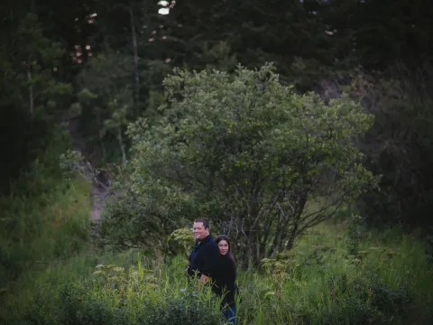Small couple standing in a green landscape under a stormy sky