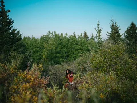 Small couple framed in green hills and trees during an outdoor engagement session