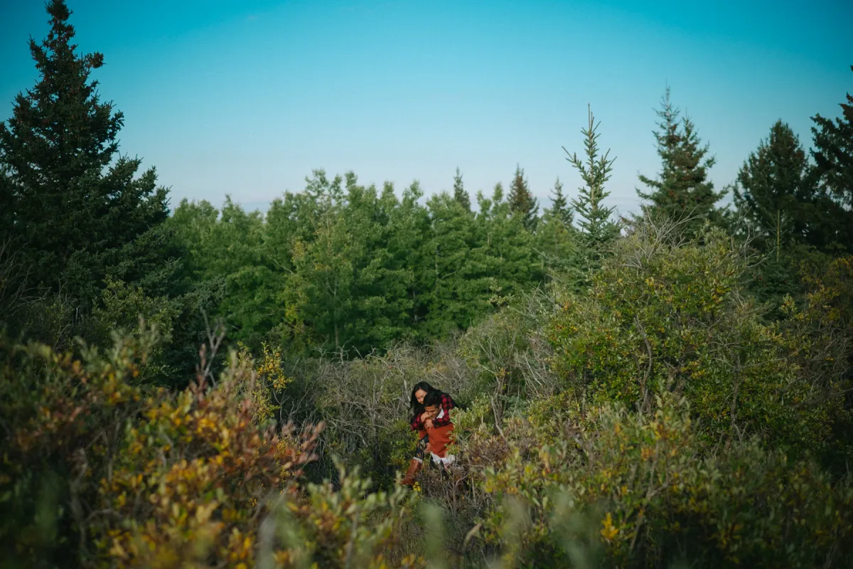 Small couple framed in green hills and trees during an outdoor engagement session