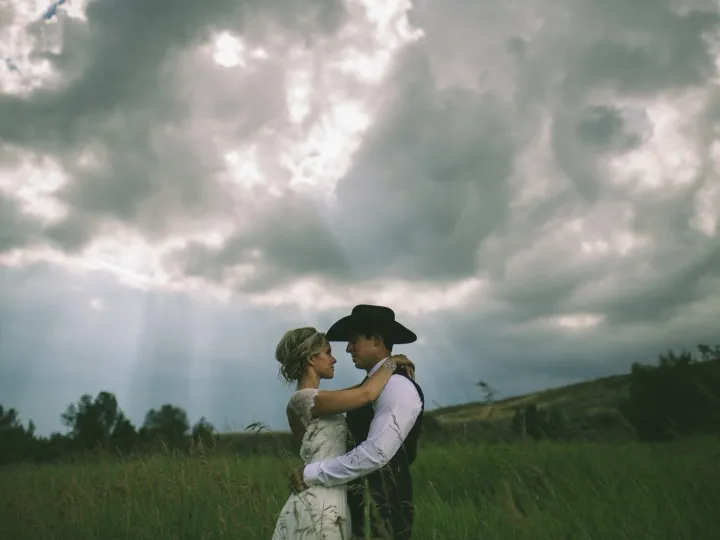 Couple holding each other beneath a dramatic prairie sky
