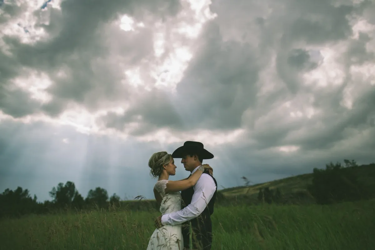 Couple holding each other beneath a dramatic prairie sky