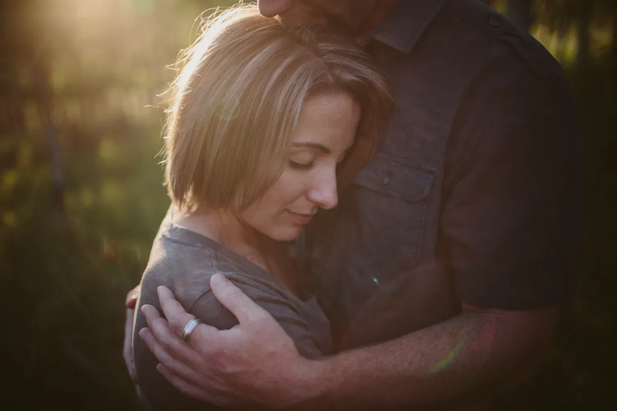 Woman resting against her partner in soft light during an engagement session