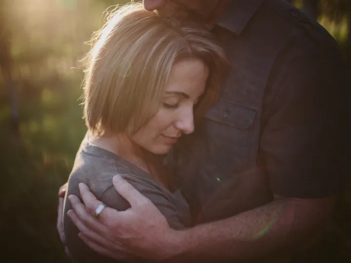 Woman resting against her partner in soft light during an engagement session