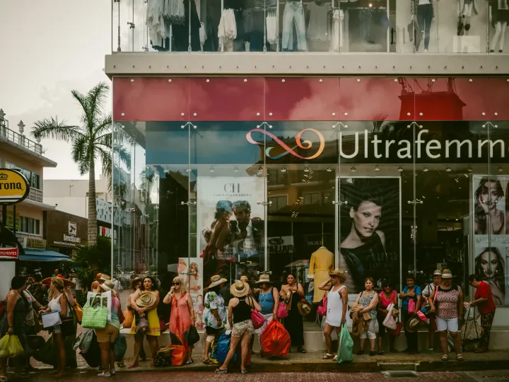 Crowd gathered in front of a colourful storefront on a busy city street