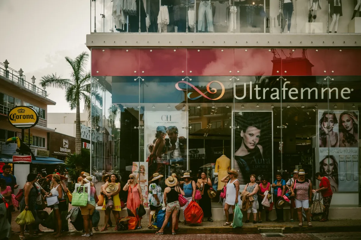 Crowd gathered in front of a colourful storefront on a busy city street