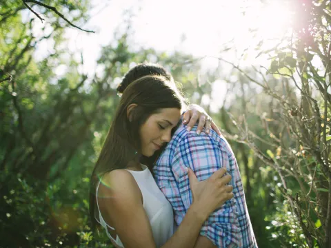 Couple holding each other with bright sun flare during an engagement session