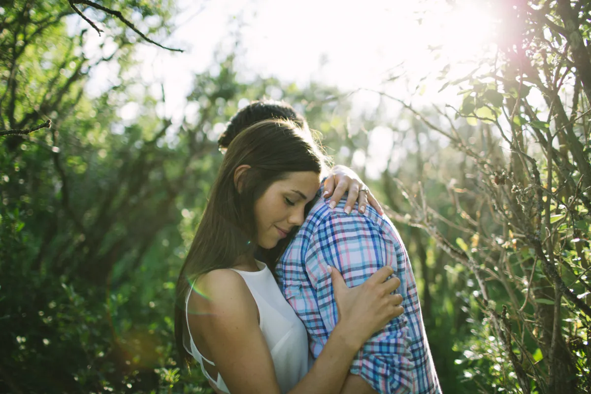 Couple holding each other with bright sun flare during an engagement session