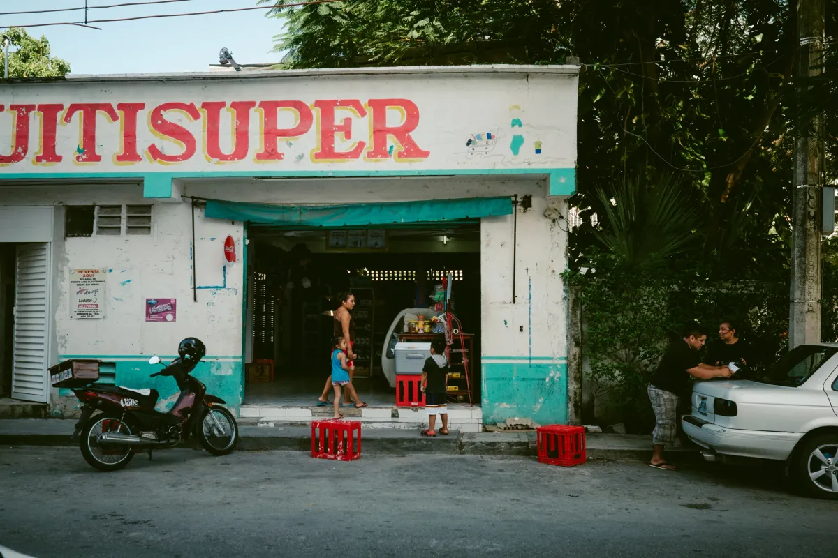 Small street supermarket with people resting in the shade outside