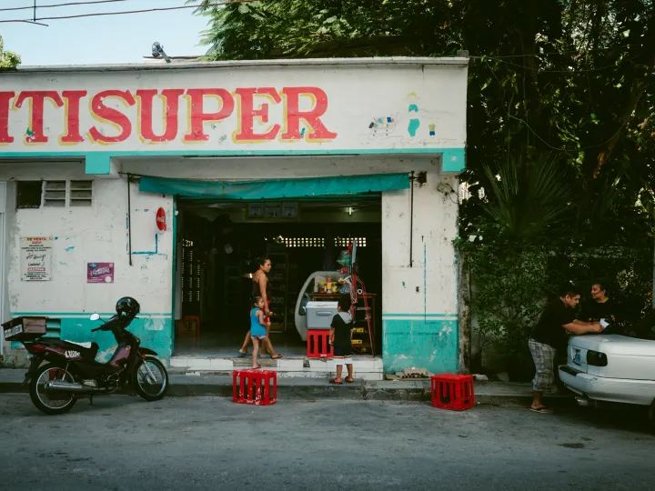 Small street supermarket with people resting in the shade outside