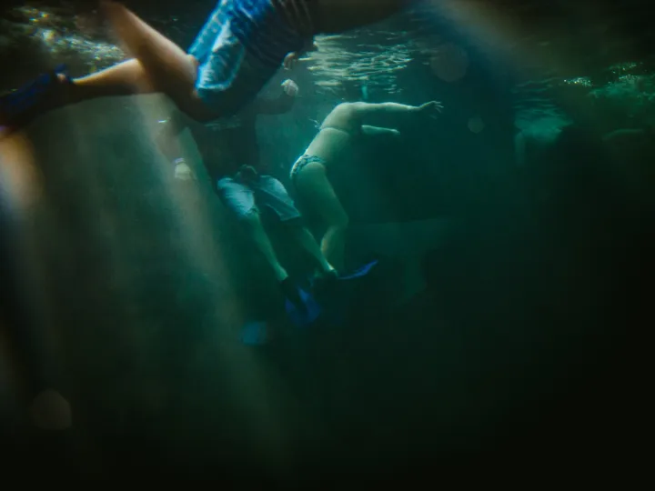 Swimmer moving underwater through green light and reflections