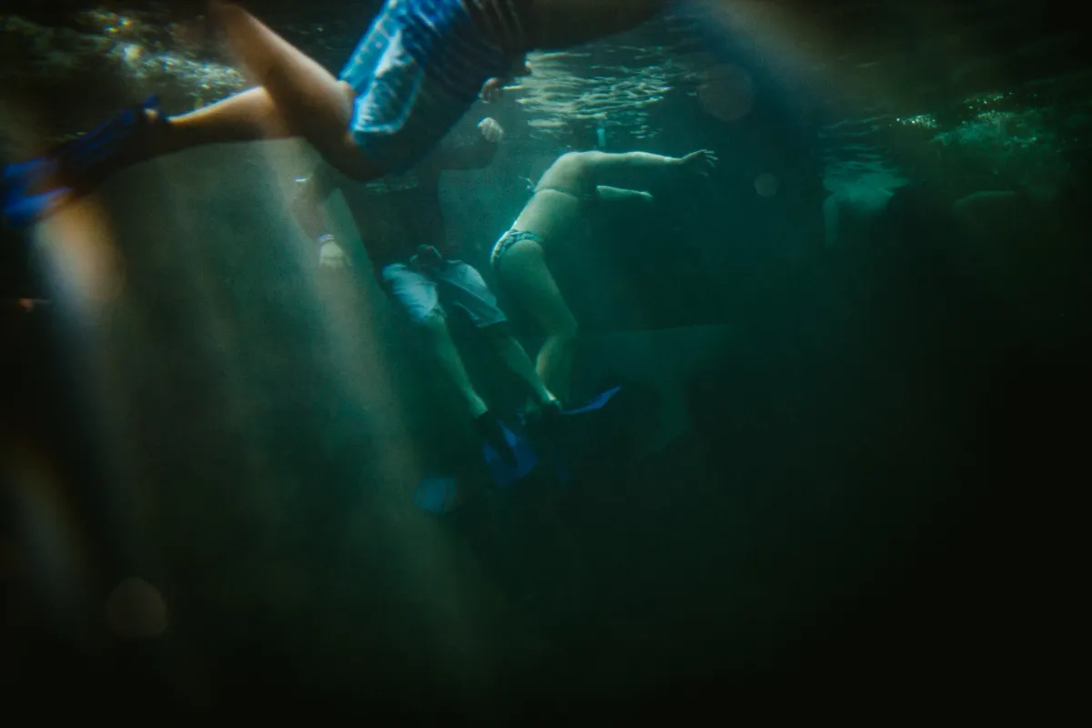Swimmer moving underwater through green light and reflections