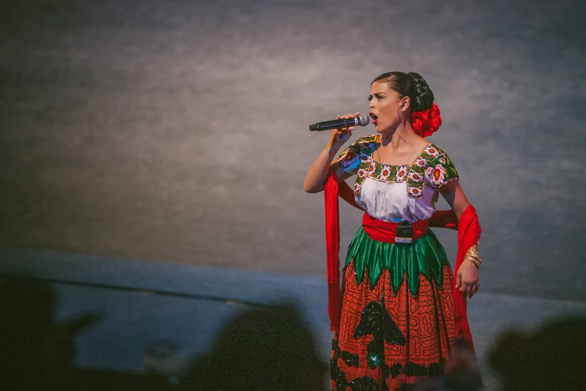 Singer in a red costume performing against a muted wall
