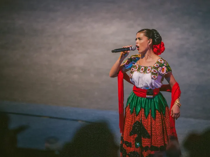 Singer in a red costume performing against a muted wall