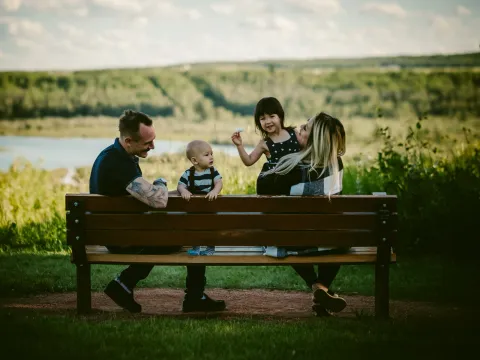 Family sitting together on a bench outdoors