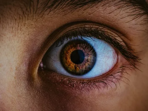 Close photograph of an eye reflecting blue light