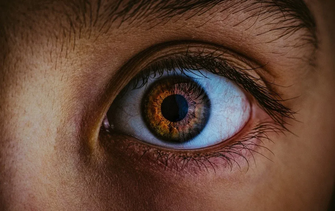 Close photograph of an eye reflecting blue light