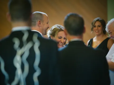 Close-up of a blonde bride laughing among wedding guests indoors