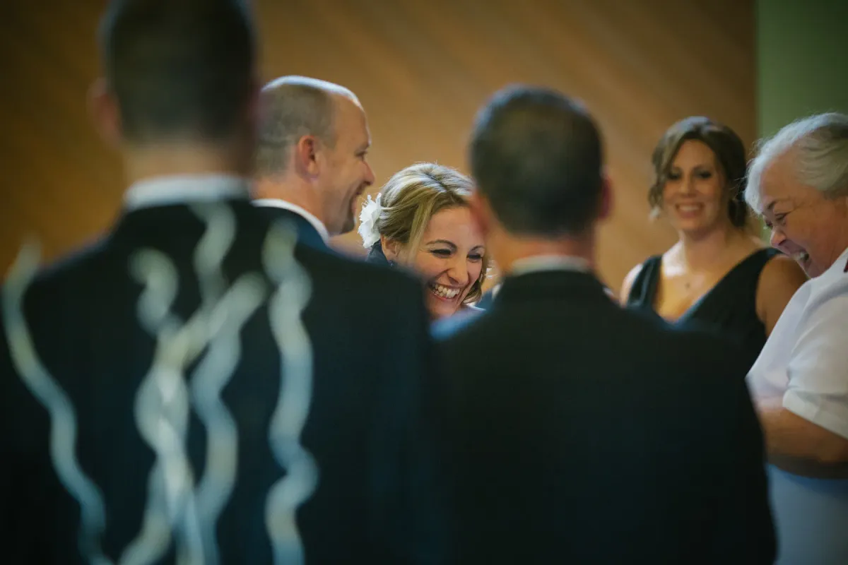 Close-up of a blonde bride laughing among wedding guests indoors
