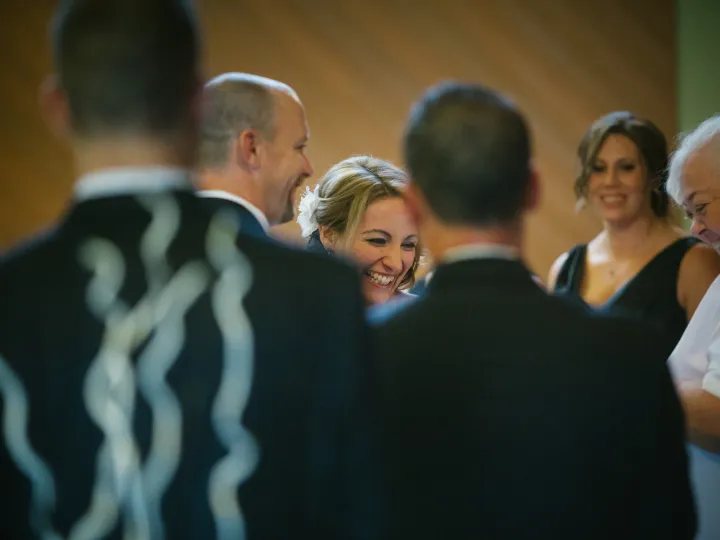 Close-up of a blonde bride laughing among wedding guests indoors