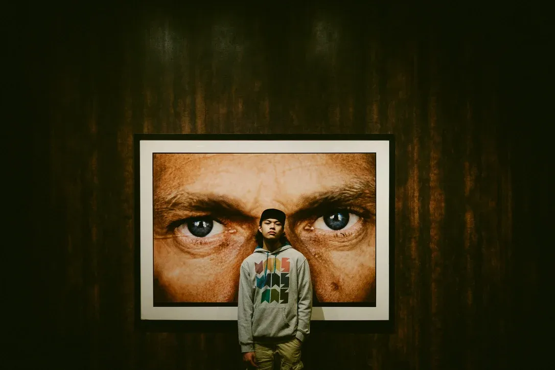 Person standing beneath a large poster of eyes
