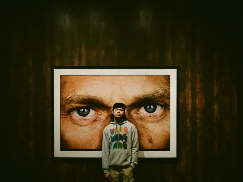 Person standing beneath a large poster of eyes