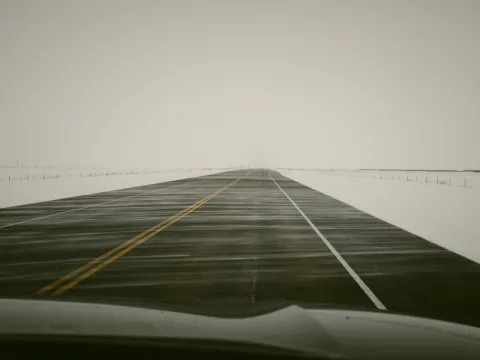 Foggy road disappearing into a pale landscape