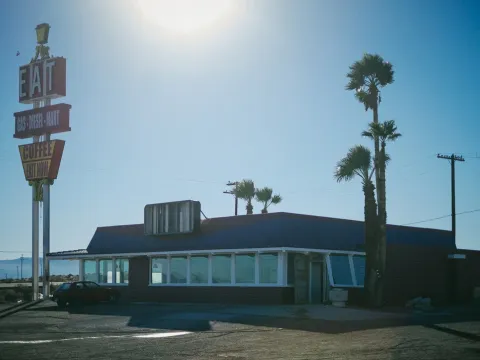 Vintage roadside sign and low building in bright sun