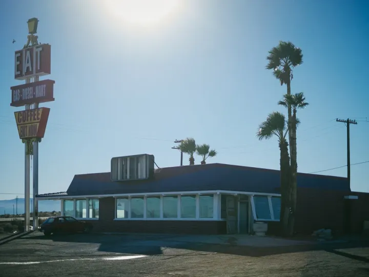 Vintage roadside sign and low building in bright sun