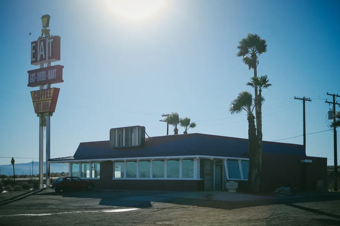 Vintage roadside sign and low building in bright sun