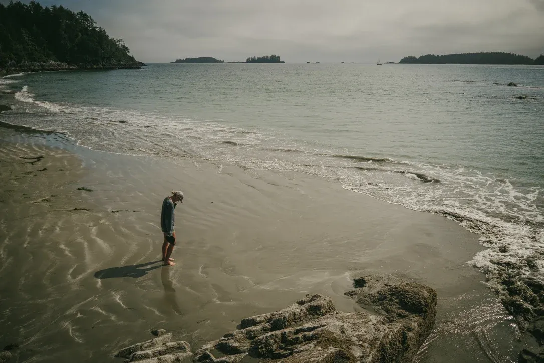 Person standing alone on wet sand near the waterline