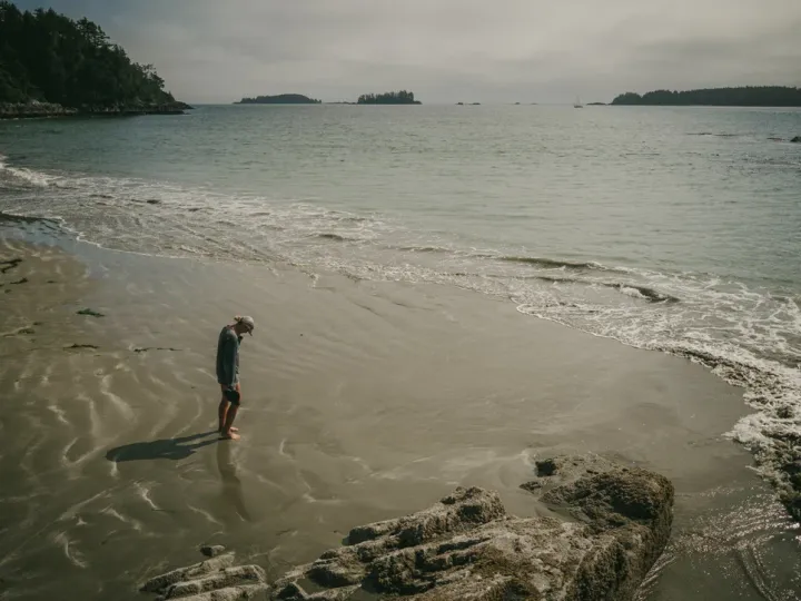 Person standing alone on wet sand near the waterline