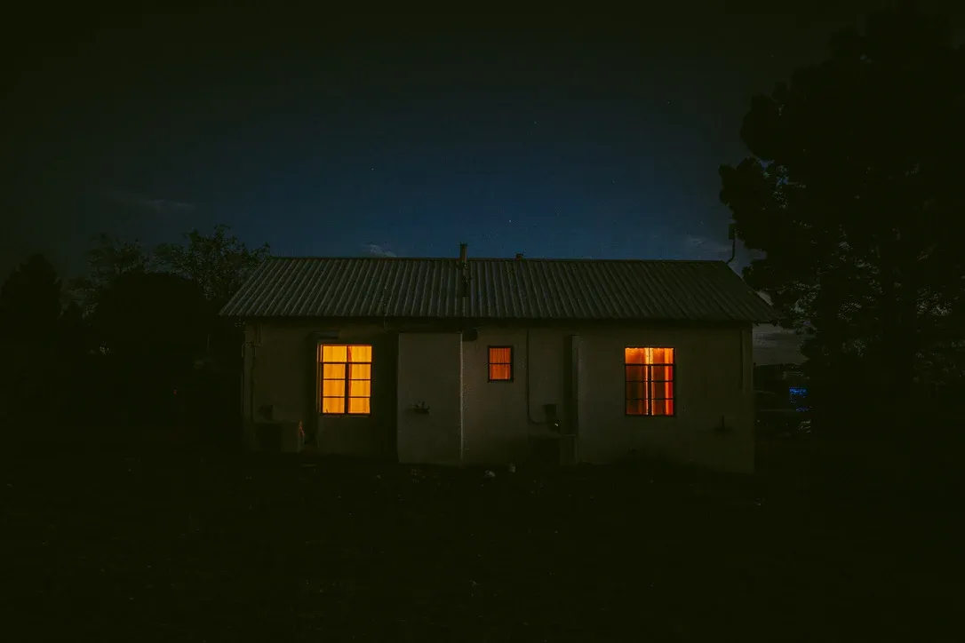 Small dark house with two warm lit windows at night