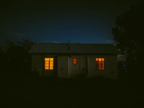 Small dark house with two warm lit windows at night