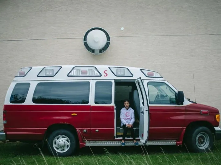 Girl sitting in the side door of a red fire chief vehicle