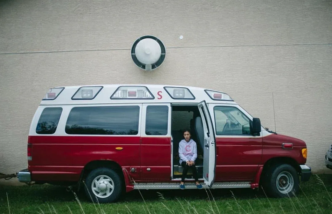 Girl sitting in the side door of a red fire chief vehicle