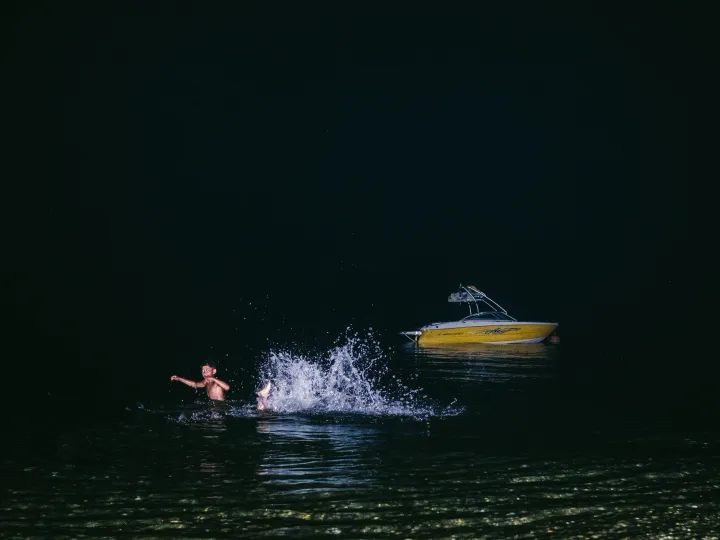 Wakeboarder cutting through dark lake water with a bright splash