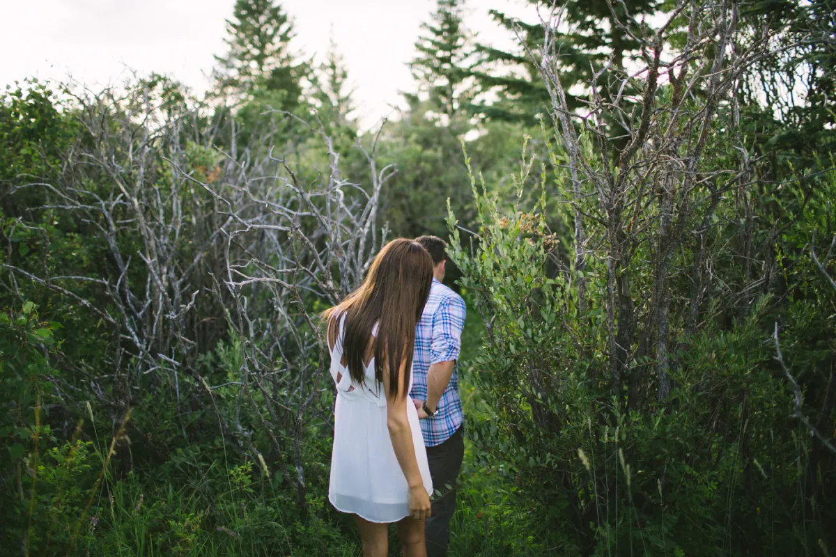Couple walking away through green brush during an engagement session