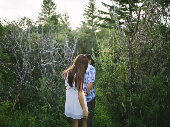 Couple walking away through green brush during an engagement session